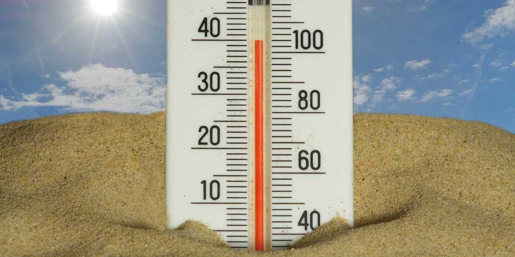 Thermometer stuck in the sand under a hot sun, reading 40 degrees C and 104 degrees F