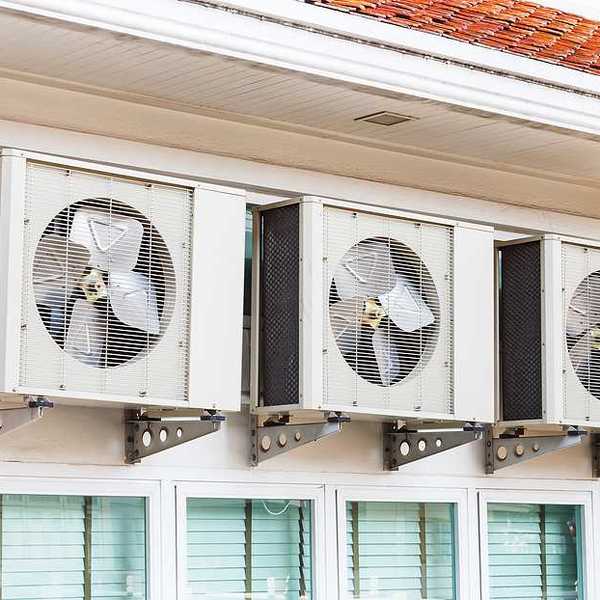 Three air conditioning units installed on a wall above windows