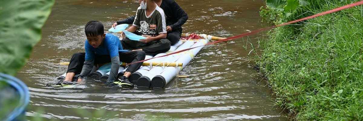 Three boys on a homemade raft being towed to shore in a water rescue