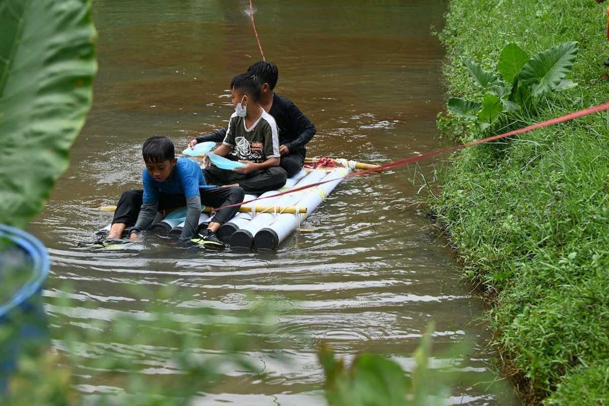 Three boys on a homemade raft being towed to shore in a water rescue