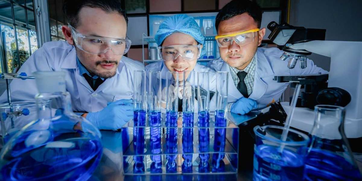 Three Chinese scientists scrutinizing six test tubes of blue liquid
