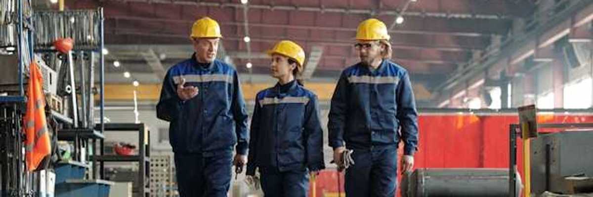 Three factory workers walking through a factory
