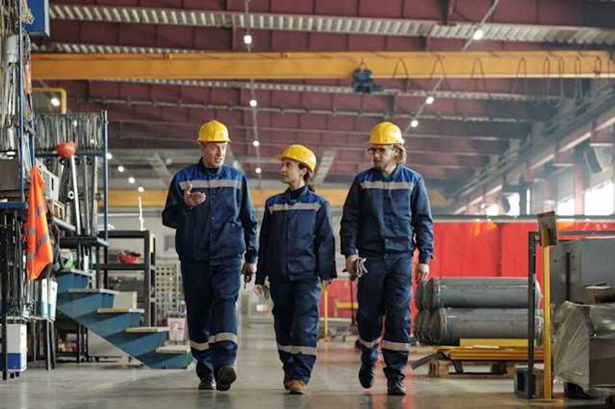 Three factory workers walking through a factory