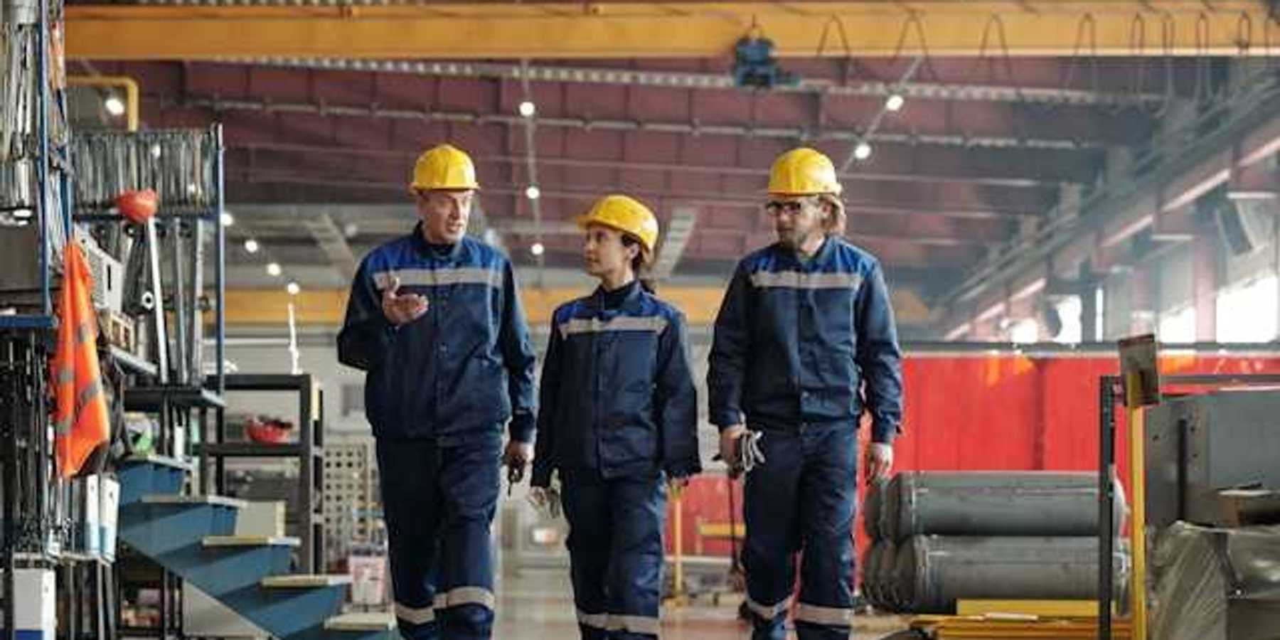 Three factory workers walking through a factory