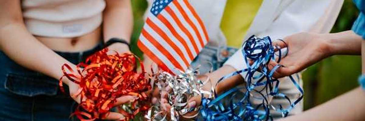 Three people standing in a circle holding a small American flag and red, silver and blue ribbons