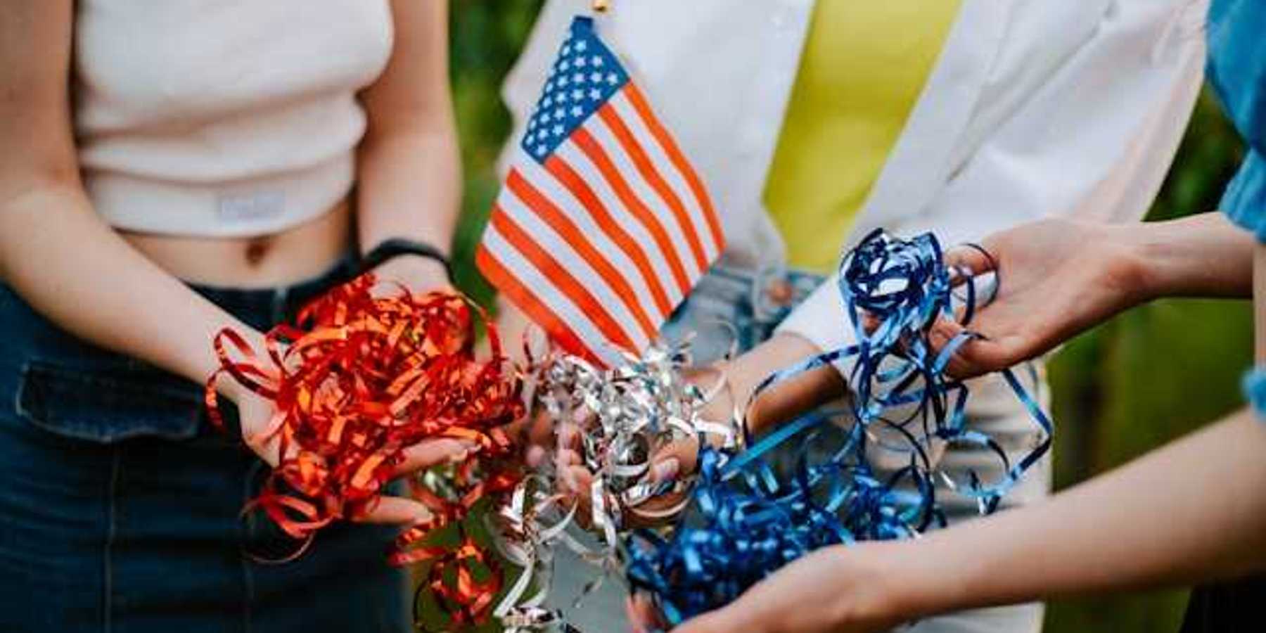 Three people standing in a circle holding a small American flag and red, silver and blue ribbons