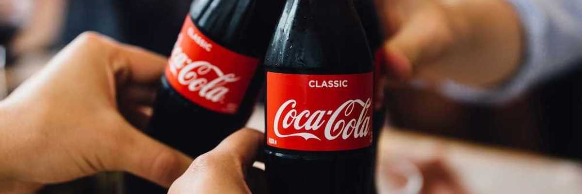 Three people, with only hands visible toasting with bottles of Coca Cola
