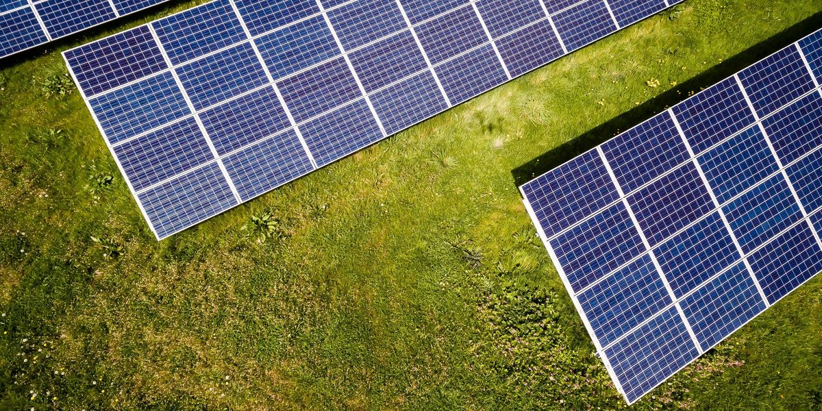Three solar panels viewed from above on a green field.