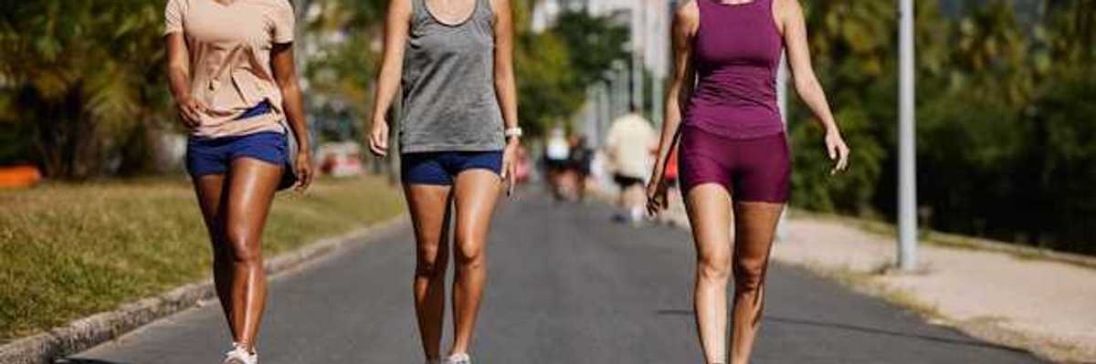 Three women wearing active wear walking on a sunny path