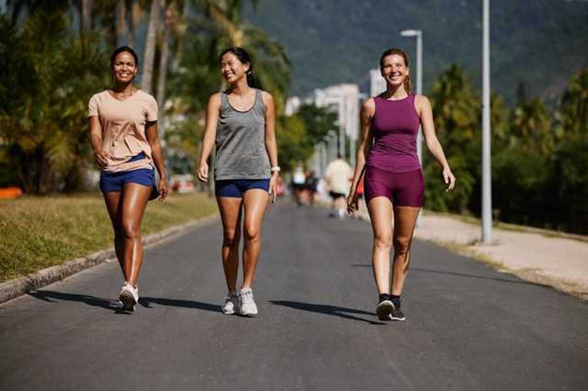 Three women wearing active wear walking on a sunny path