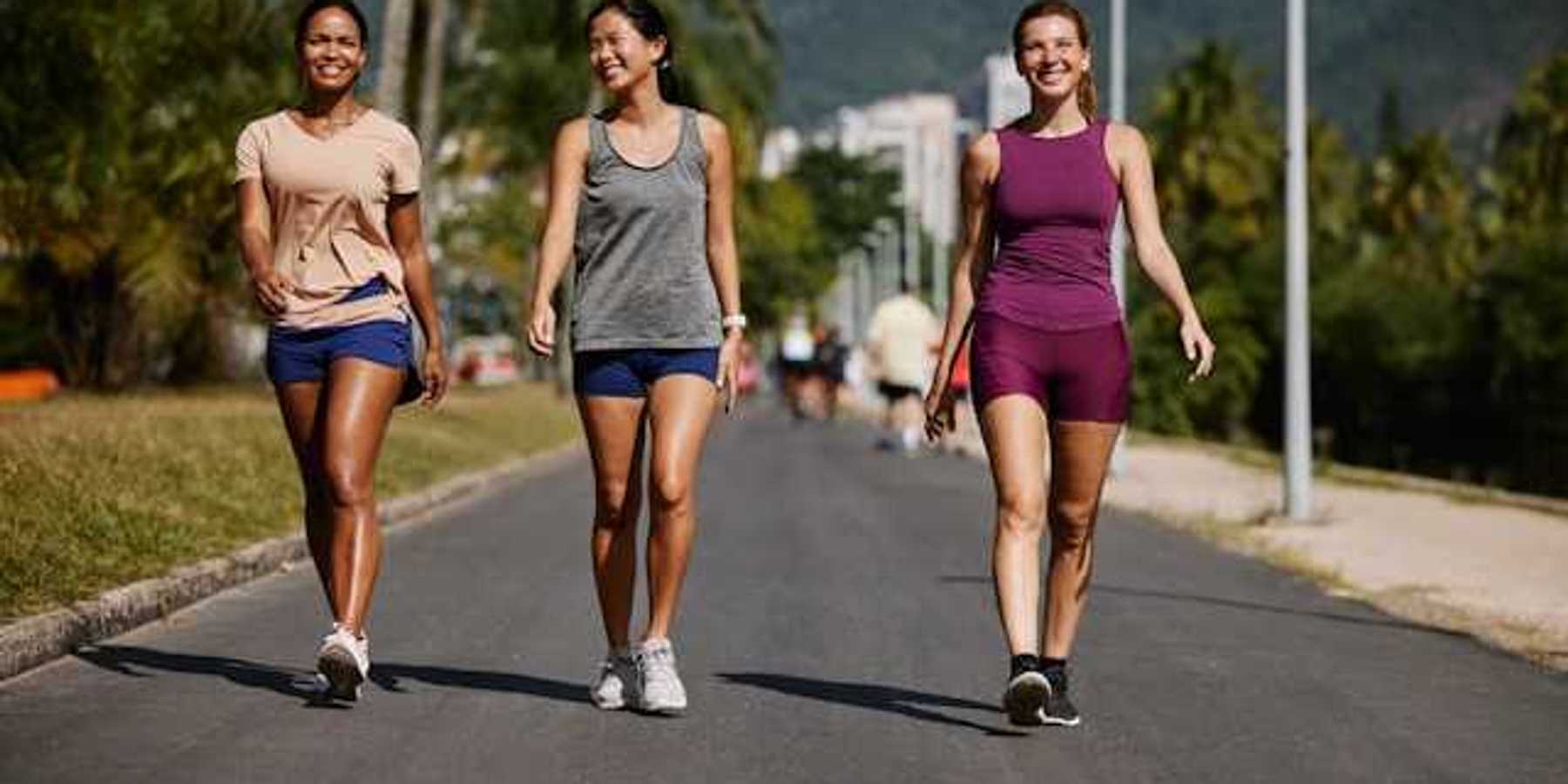 Three women wearing active wear walking on a sunny path