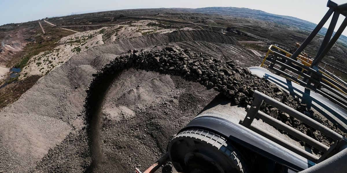 Tractor pouring coal onto coal pile at a mining site.