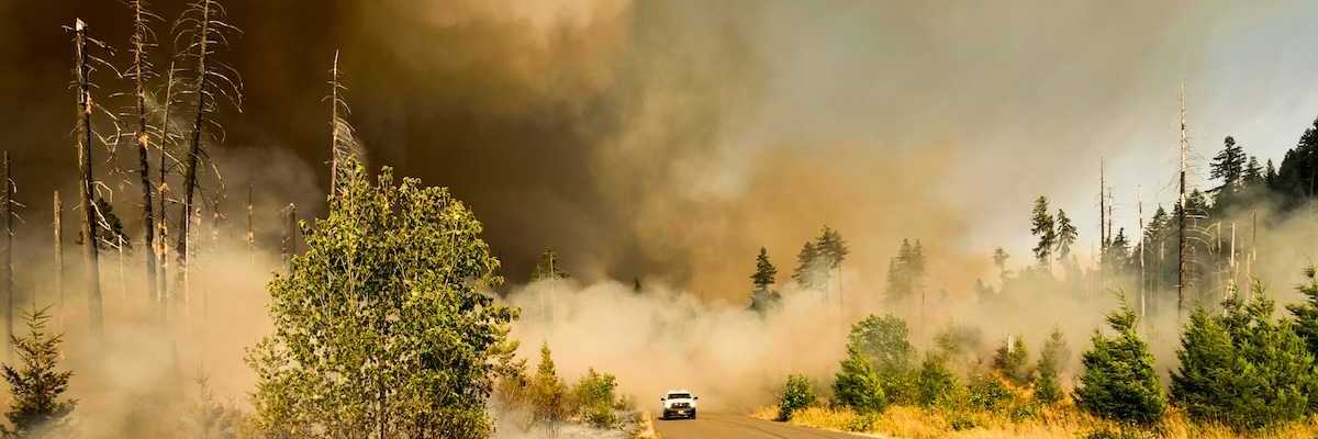 Truck driving out of wildfire smoke on highway