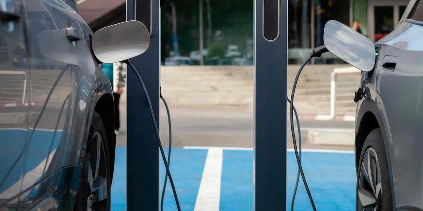 Two adjacent EVs being recharged at charging station.