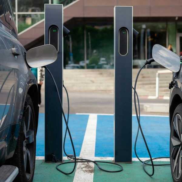 Two adjacent EVs being recharged at charging station.