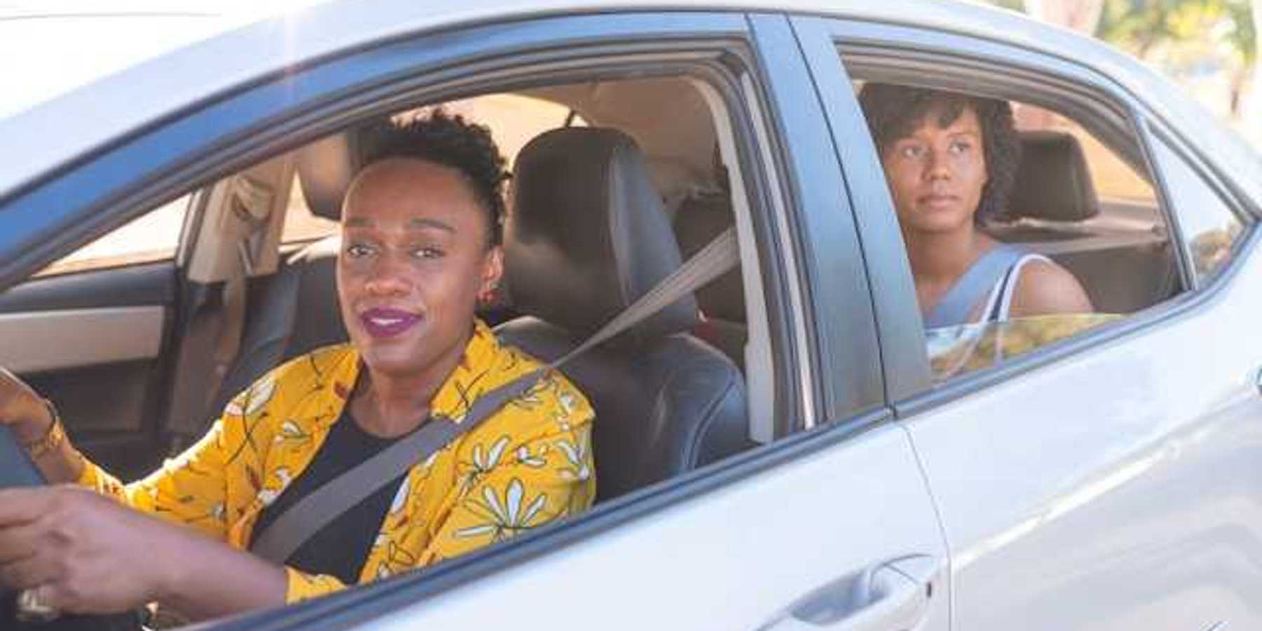 Two African woman in a car, a driver and a back-seat passenger on a sunny day
