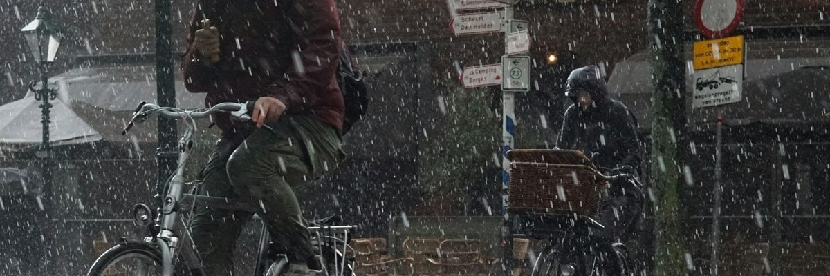 Two bicyclists riding single-file in a downpour