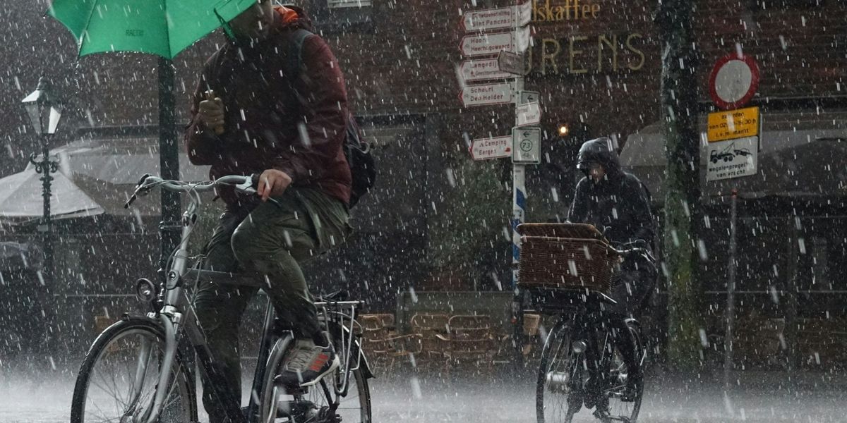 Two bicyclists riding single-file in a downpour