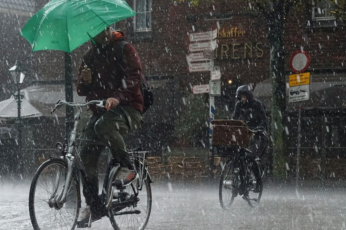 Two bicyclists riding single-file in a downpour