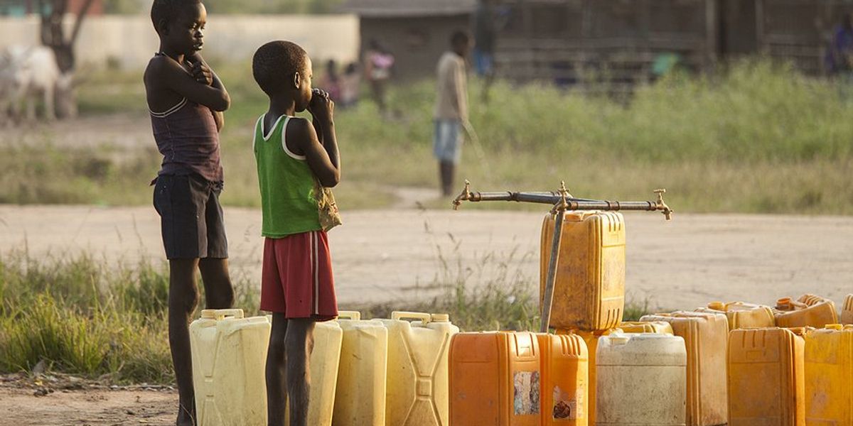 Two children standing by plastic jugs