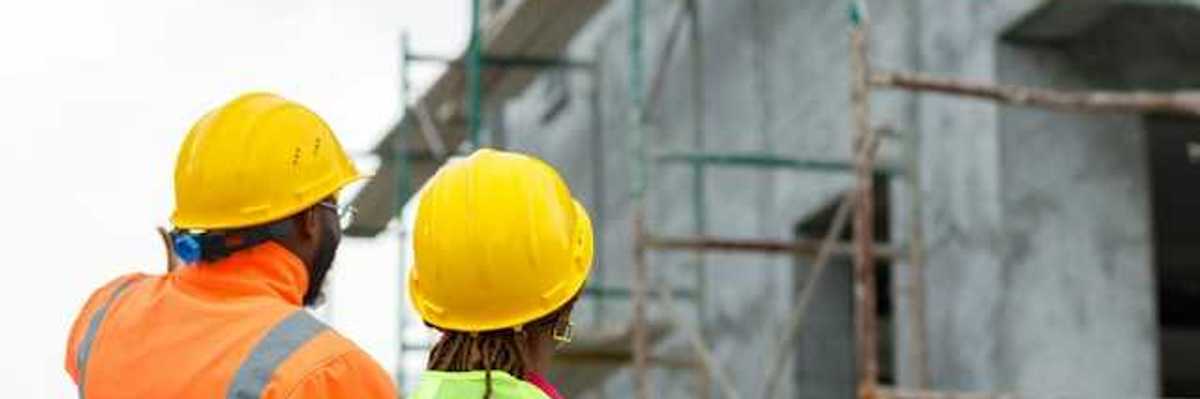 Two construction workers looking up at scaffolding on a new build