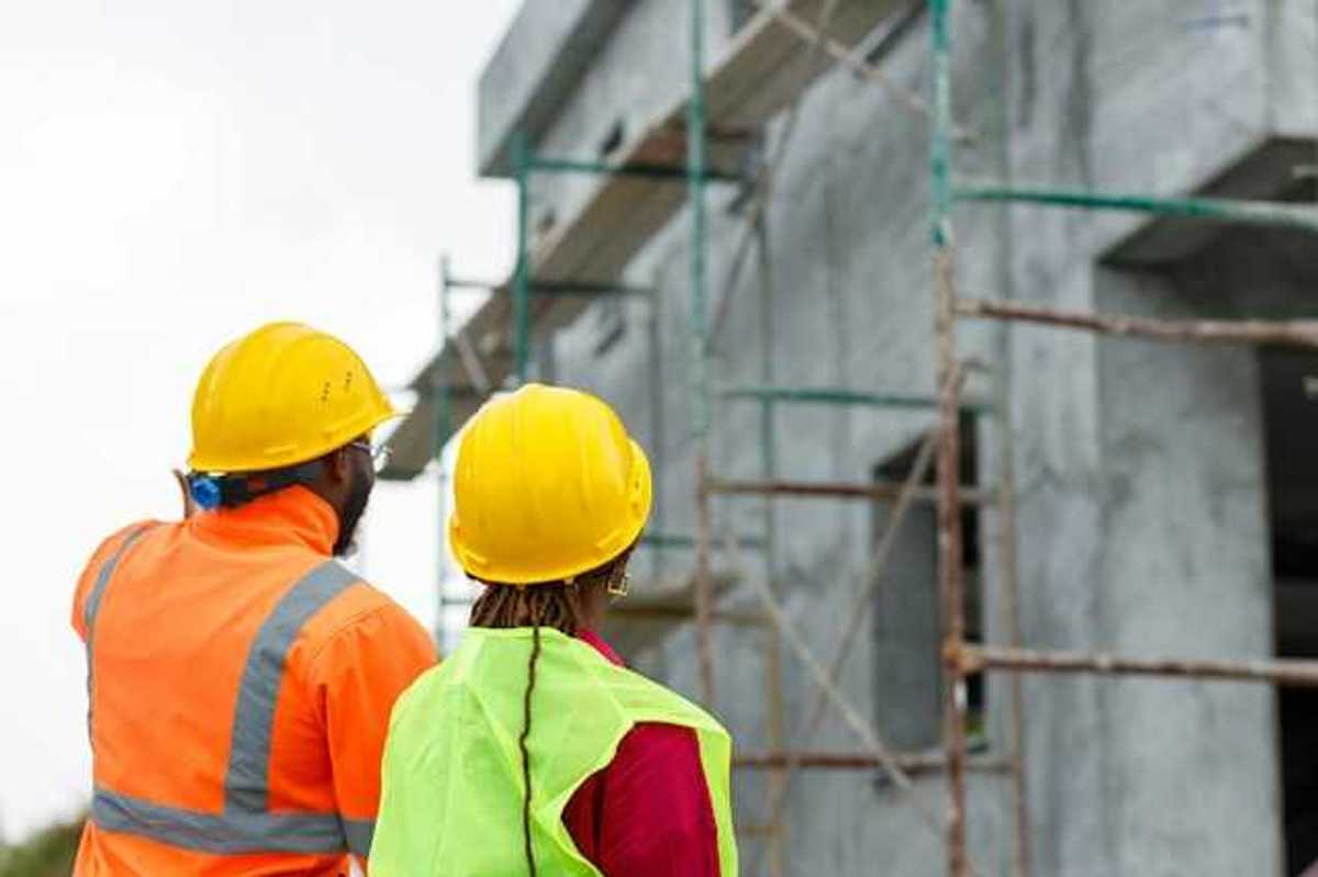 Two construction workers looking up at scaffolding on a new build