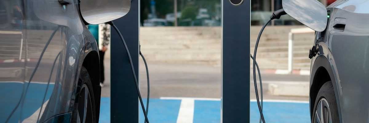 two EVs, side by side, being recharged at charging stations