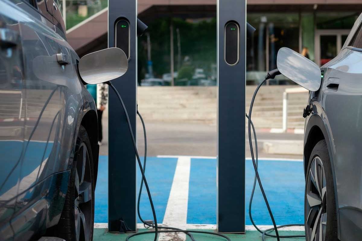 two EVs, side by side, being recharged at charging stations