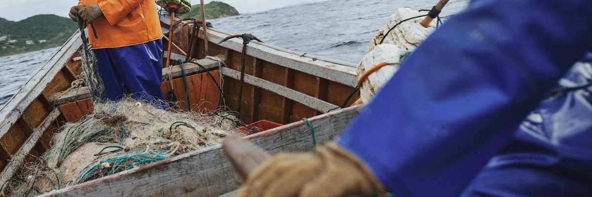 Two fishermen deploying nets from a small boat