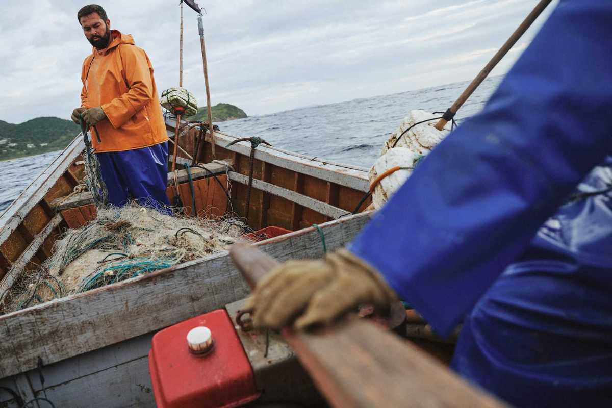 Two fishermen deploying nets from a small boat