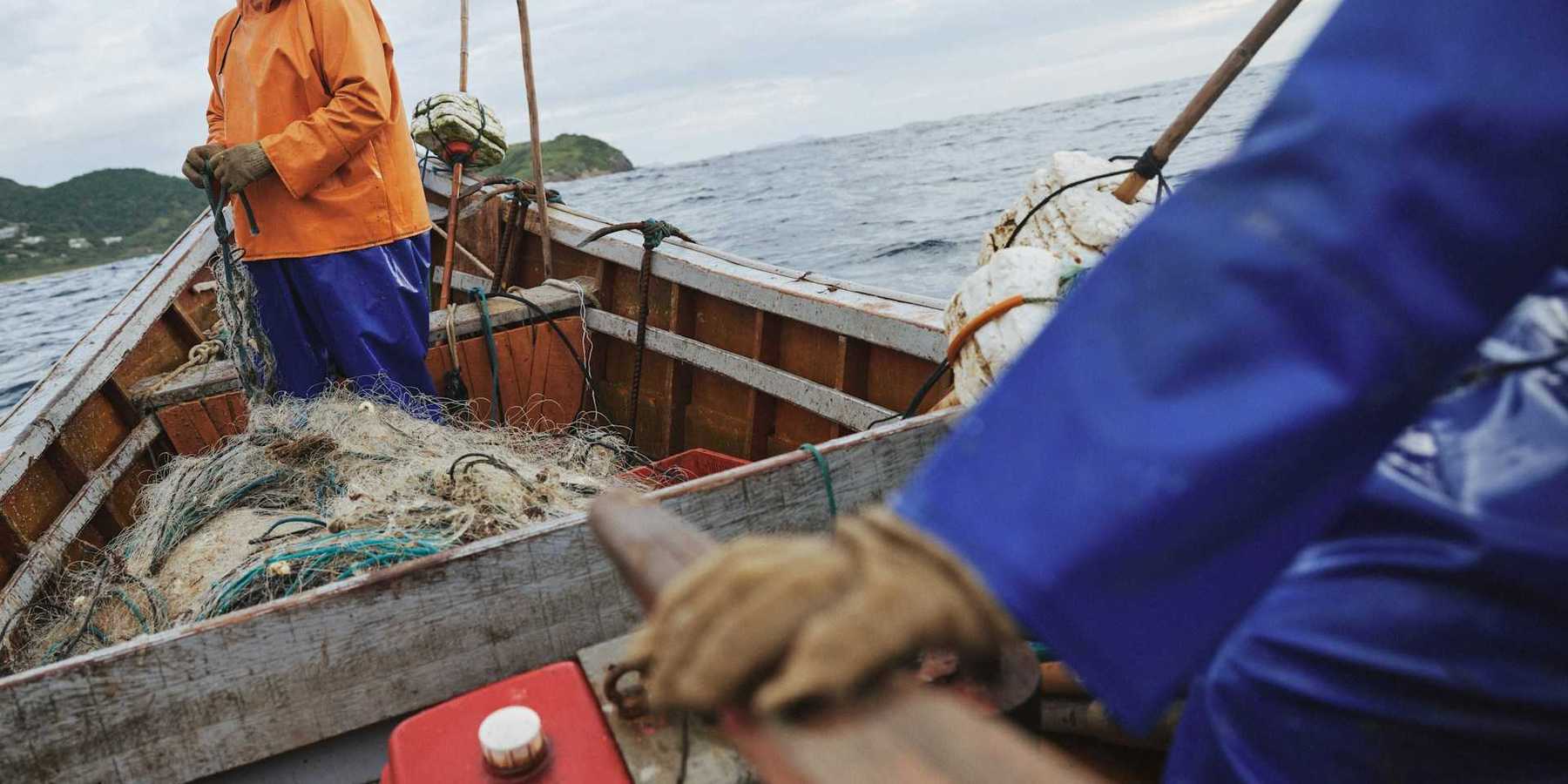 Two fishermen deploying nets from a small boat