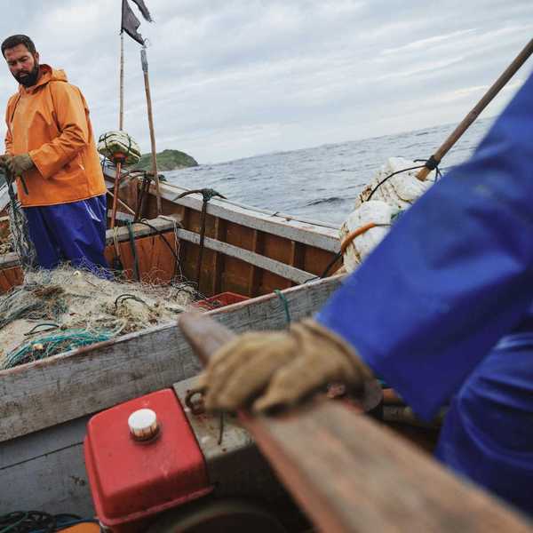 Two fishermen deploying nets from a small boat
