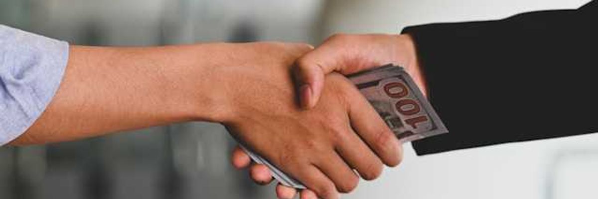 Two hands clasping with money in their hands