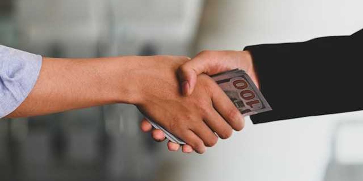 Two hands clasping with money in their hands