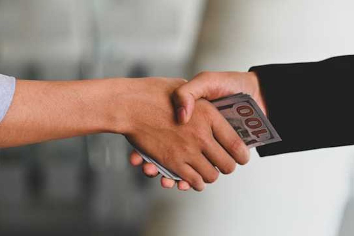 Two hands clasping with money in their hands