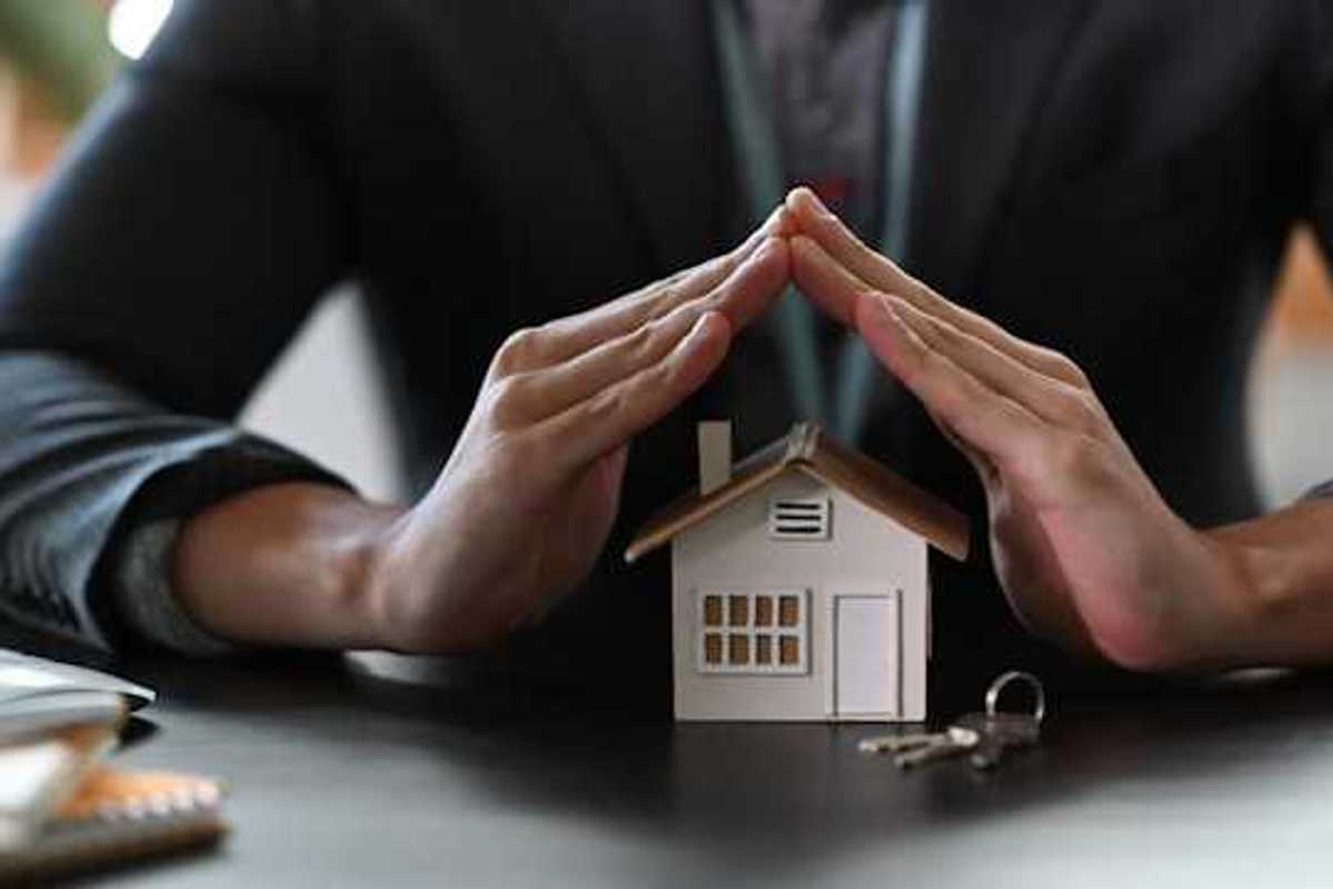 Two hands cupped over a model of a house