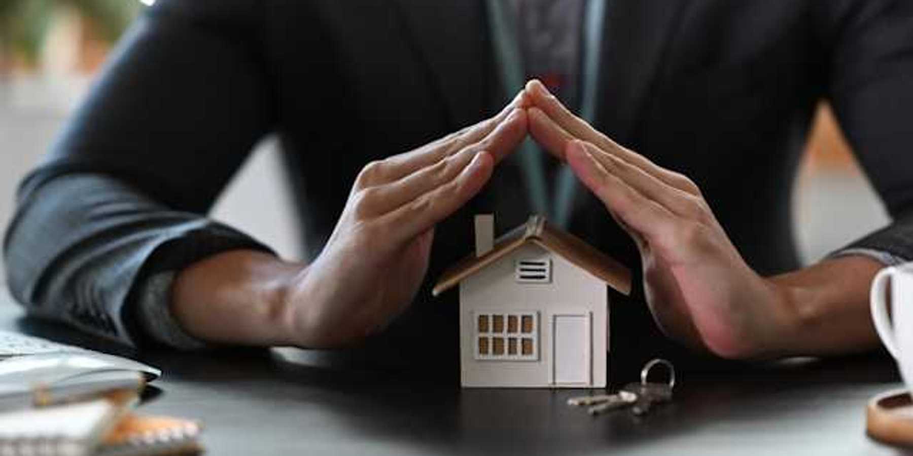 Two hands cupped over a model of a house
