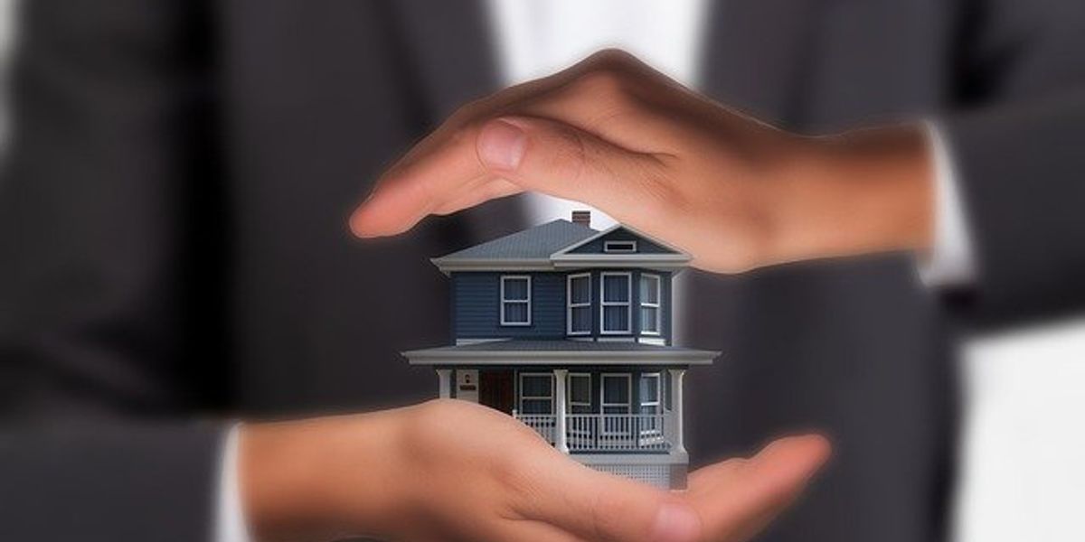 Two hands holding a minature house