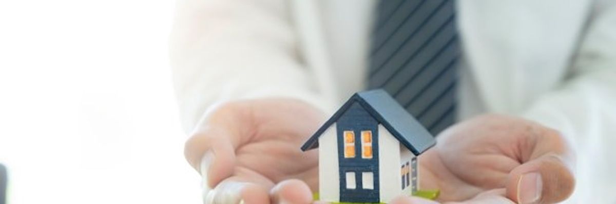 Two hands holding a model of a house in their hands
