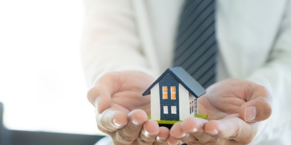 Two hands holding a model of a house in their hands
