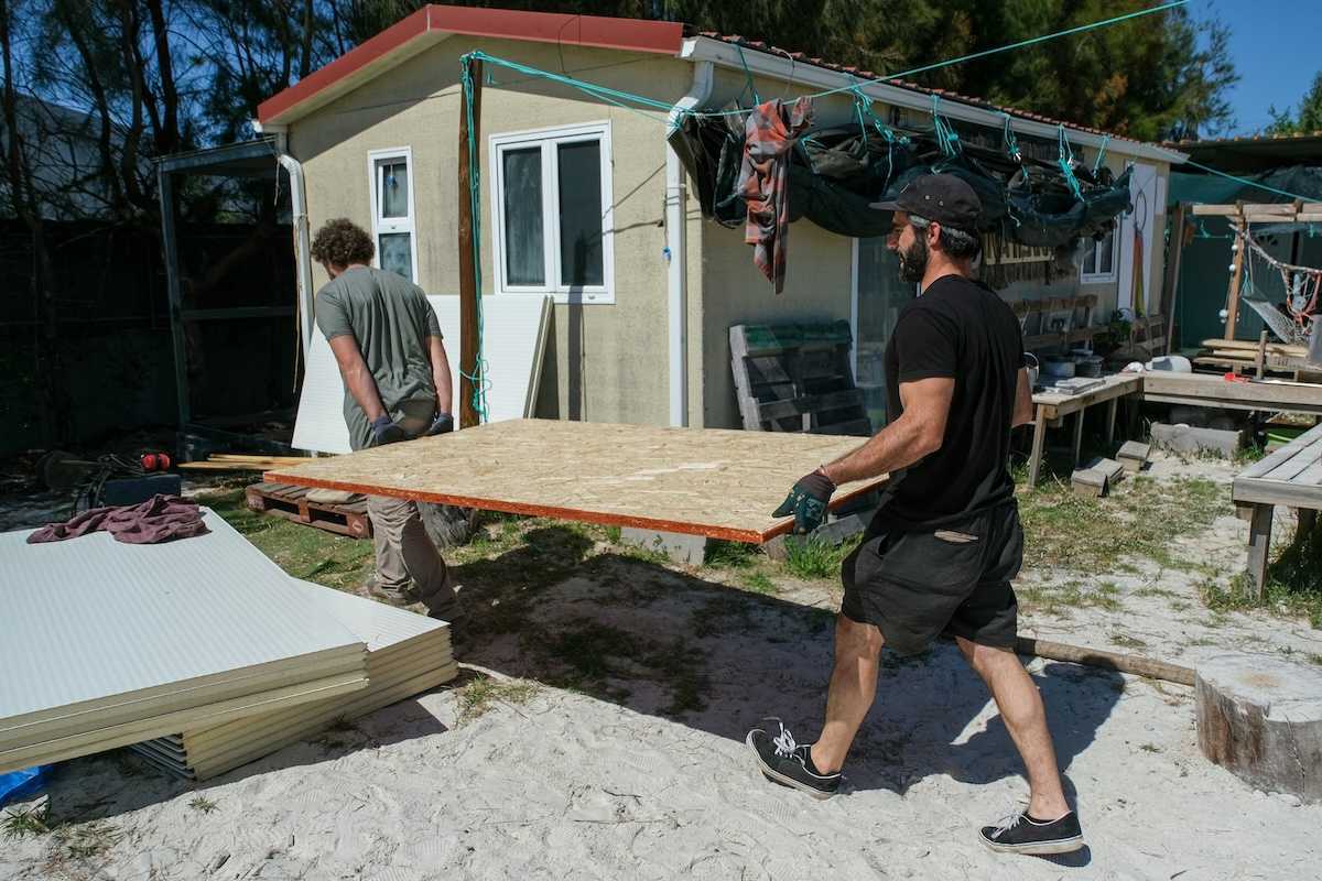 Two men carrying sheets of chipboard for structural repair or construction