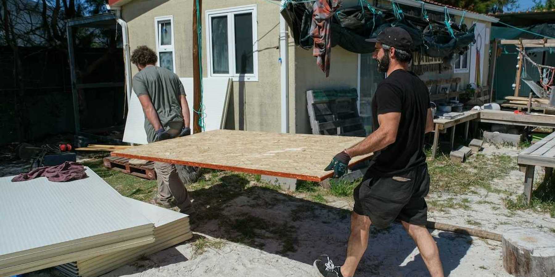 Two men carrying sheets of chipboard for structural repair or construction