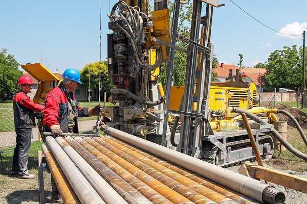 Two men drilling a geothermal well for a residential geothermal heat pump.
