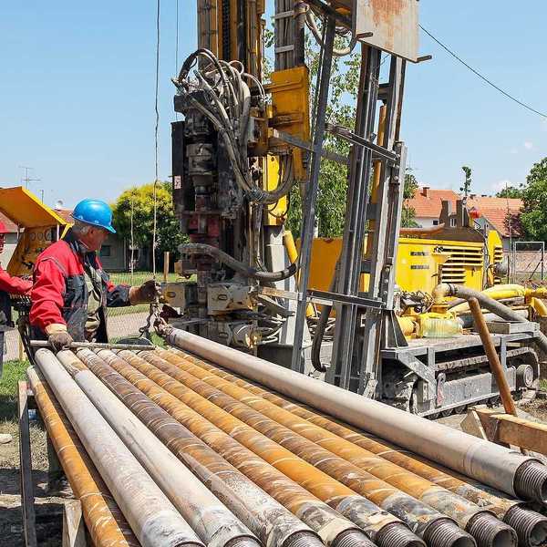 Two men drilling a geothermal well for a residential geothermal heat pump.