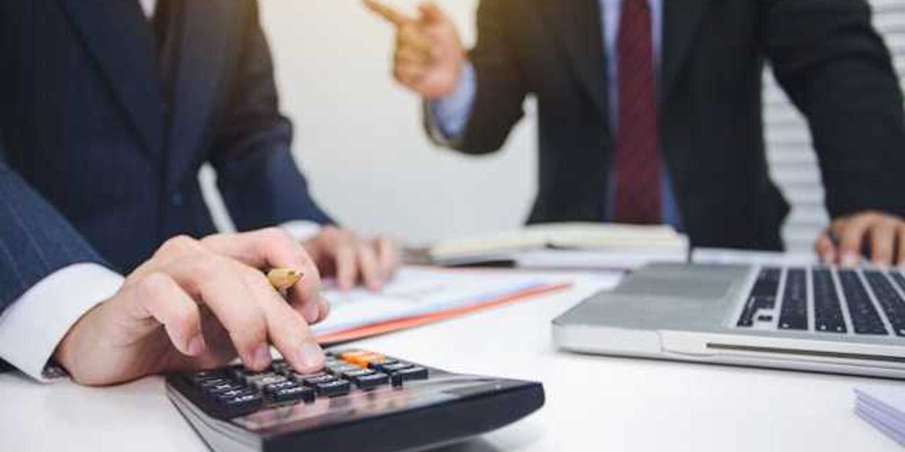 Two men in suits tallying numbers on a calculator