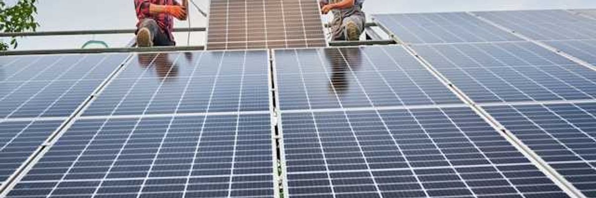 Two men installing solar panels on a roof