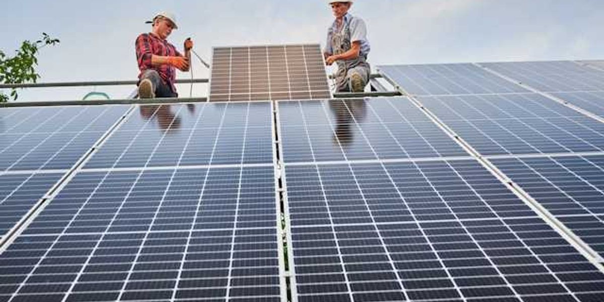 Two men installing solar panels on a roof