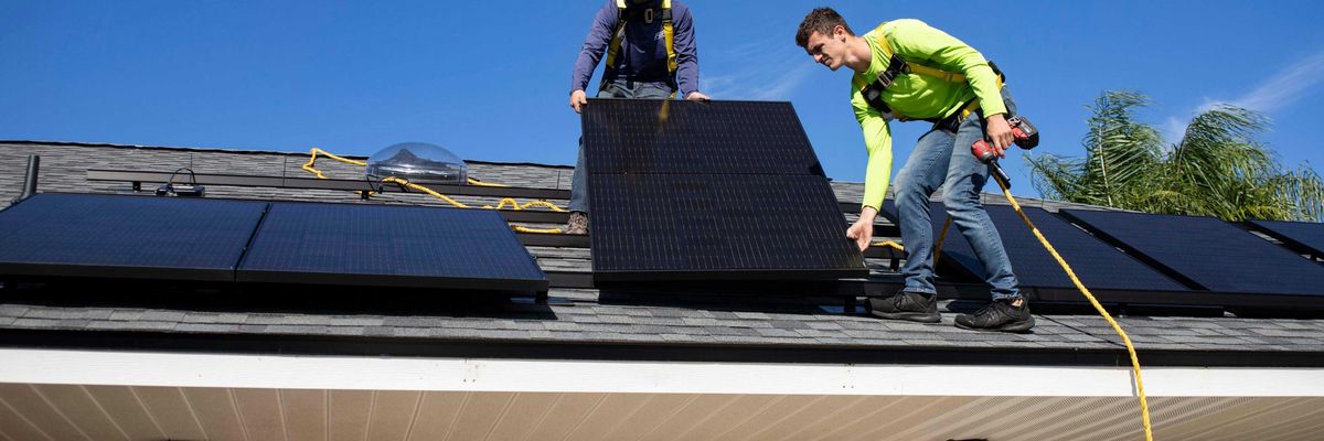 Two men installing solar panels on a roof