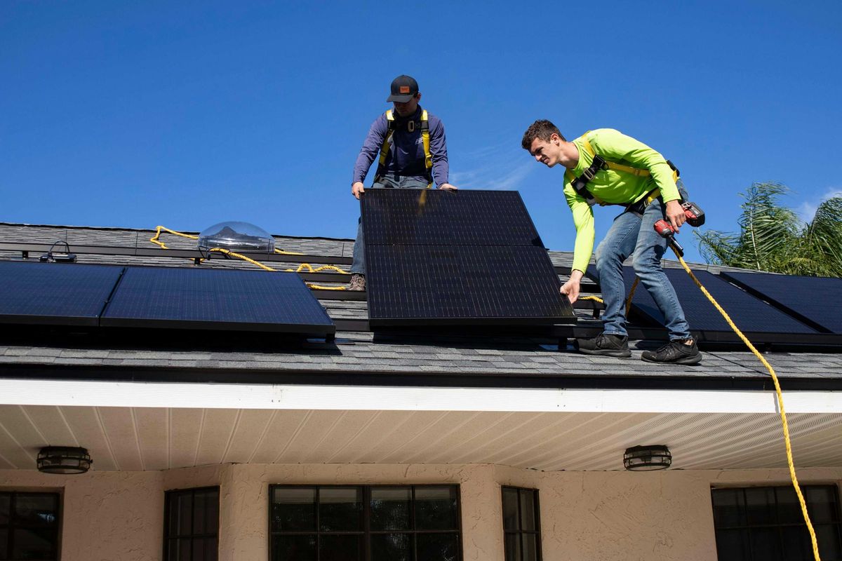 Two men installing solar panels on a roof