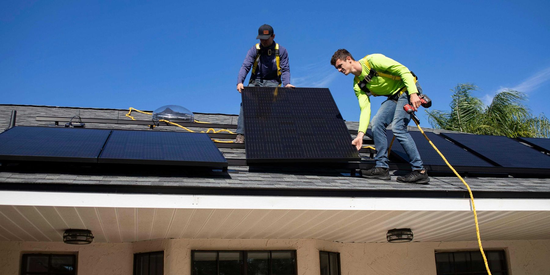 Two men installing solar panels on a roof